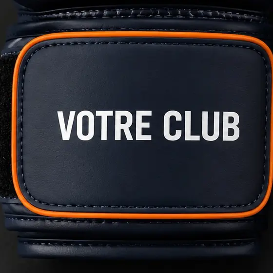 Gros plan sur la bande de serrage velcro portant la mention « votre club », coloris marine et orange